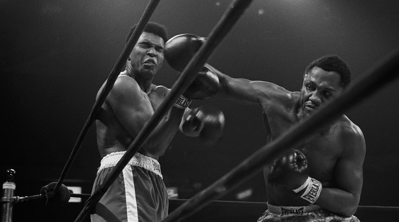                             Le champion poids lourd Joe Frazier lâche un coup herculéen contre Mohamed Ali pendant le Combat du siècle